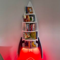 there is a book shelf with books in the shape of a rocket ship on it