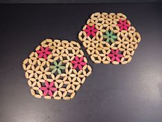 two wooden coasters made to look like hexagonal flowers on a black surface