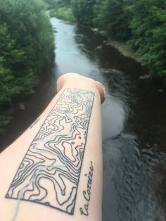 a person's arm with a map tattoo on it and trees in the background