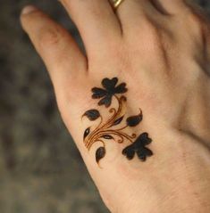 a woman's hand with a tattoo on it that has flowers and leaves painted on it