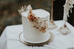 a close up of a white cake with brown flowers on the top and side, sitting on a table