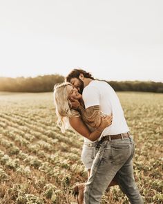 a man and woman kissing in the middle of a field