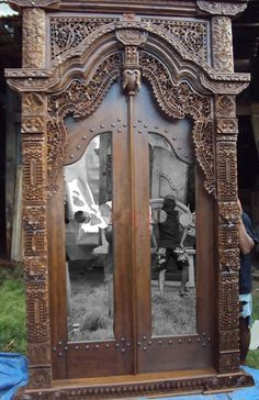 an ornate wooden mirror is shown in the middle of a room with blue tarp