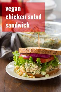 a chicken salad sandwich with lettuce, tomato and onion on a white plate