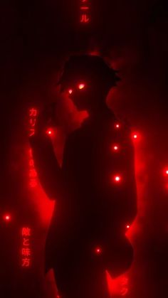 a person standing in the dark with red lights on their face and hands behind them