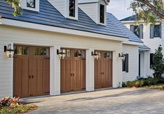 two garage doors are open in front of a white house with brown trim and windows