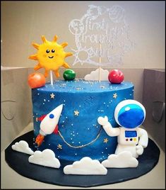 a blue cake with an astronaut and rocket on top, surrounded by stars and clouds