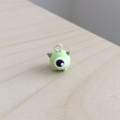 a small green monster charm sitting on top of a wooden table