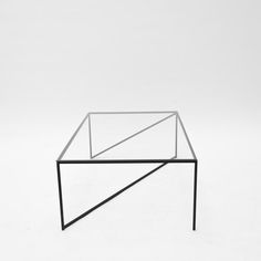 a glass table sitting on top of a white floor next to a black metal frame