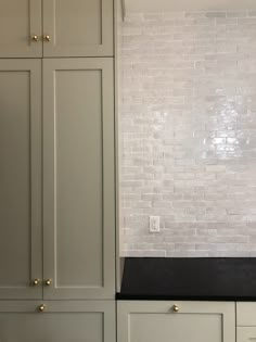 a kitchen with white brick walls and black counter tops, along with gold knobs