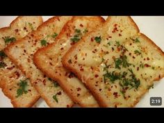 four pieces of bread with cheese and parsley on them sitting on a white plate