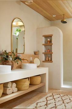 a bathroom with a sink, mirror and shelves filled with towels on the counter top