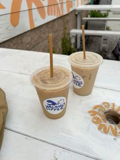 two iced coffees sitting on top of a white table