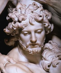 a statue of a man with curly hair and beards holding his hands on his chest