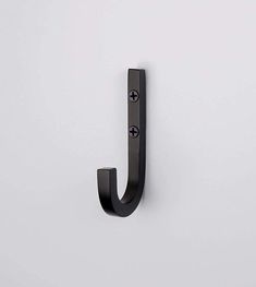 a black metal hook on the side of a white wall with an open letter j