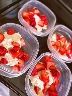 four plastic containers filled with strawberries on top of a black counter topped with whipped cream