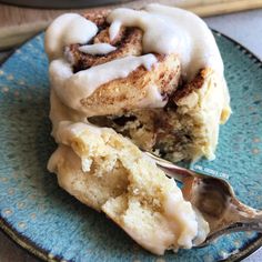 a cinnamon roll on a blue plate with a spoon