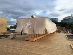 a large wooden structure on top of a wooden floor next to other wood structures and buildings