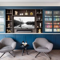 two chairs and a table in front of a large entertainment center with blue painted walls