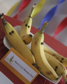 some bananas are sitting in a white bowl on a red tablecloth with streamers