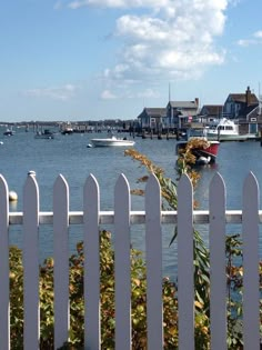 boats are in the water behind a white picket fence