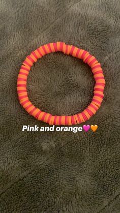 a pink and orange bracelet with hearts on the inside is laying on a gray surface