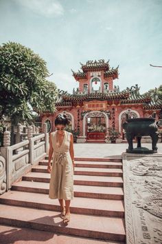 a woman standing on some steps in front of a building with an elephant statue behind her