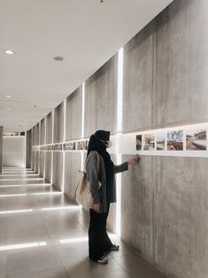 a person standing in front of a wall with pictures on it and holding onto the wall