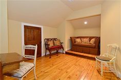 a living room filled with furniture and hard wood flooring next to a wooden door