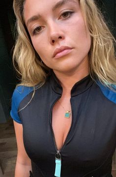 a woman wearing a black top with a blue and green necklace on her neck is looking at the camera