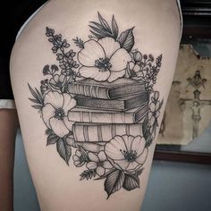 a woman's thigh with books and flowers on it