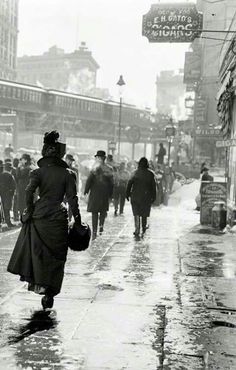 an old black and white photo of people walking in the rain