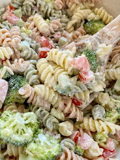 a pasta salad with broccoli and ham in a white bowl on the table