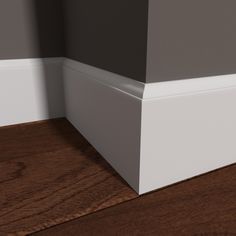 the corner of a room with wood flooring and white trim on the wall above it