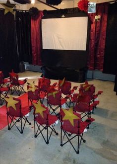 an empty room with red and yellow chairs in front of a projector screen on the wall