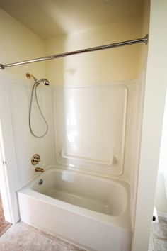 a bath tub sitting inside of a bathroom next to a shower head and toilet paper dispenser