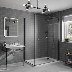 a bathroom with grey tiles and a white sink, shower stall and stand up shower