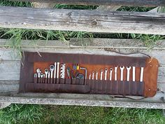 a wooden bench with a bunch of tools hanging on it's back and some grass in the background