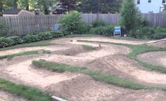 an empty skateboard park in the middle of a back yard with grass and dirt