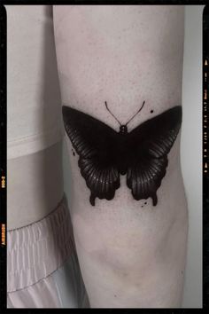 a black butterfly tattoo on the leg