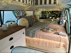 the interior of a camper with lights strung from the ceiling and bed in the foreground