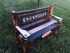 a bench that is in the grass with a chevrolet sign on it's back