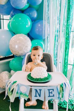 a baby sitting in a highchair with a cake on it's table