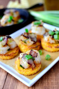 small appetizers on a plate with green onions and scallops in the background