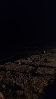 a person standing on top of a sandy beach at night