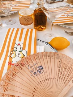 an orange and white striped table cloth with a decorative fan on it, surrounded by other place settings