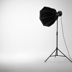 an umbrella on a tripod in front of a white background with the light attached to it