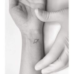 a small saturn tattoo on the left wrist and an armband is shown in this black - and - white photo