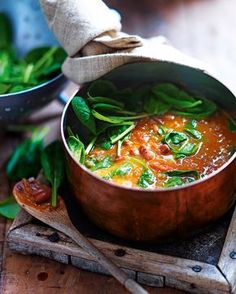 a copper pot filled with food on top of a wooden table