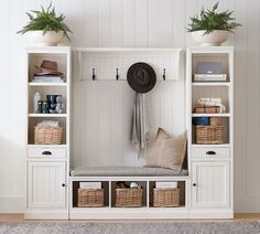 a white coat rack with baskets and hats on it next to a wall mounted shelf